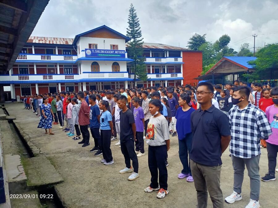 Students assembled in rows outside the school buildings.