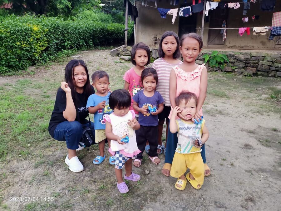 A mother with a group of young children outside their home.