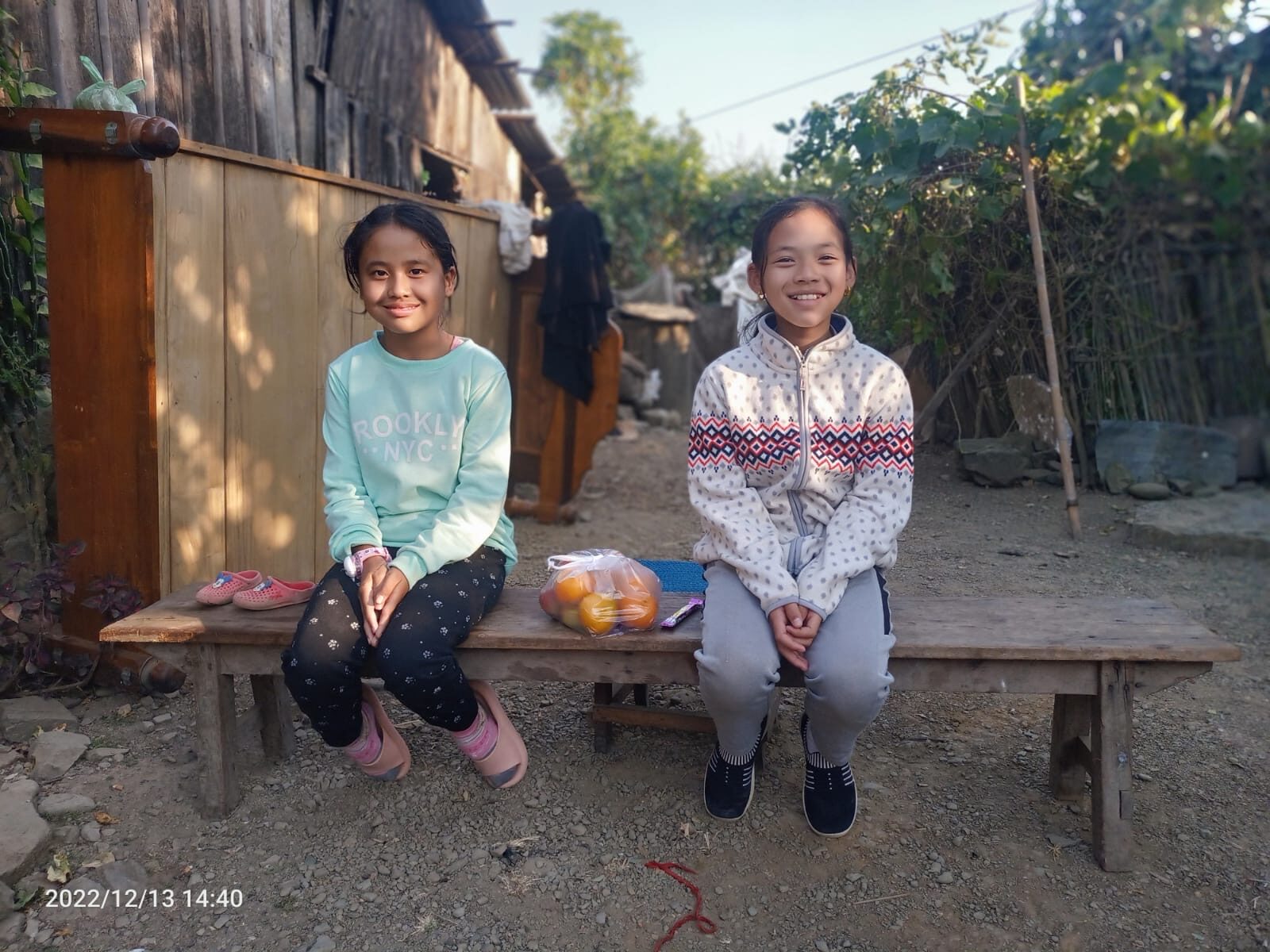 Two students sitting together on a bench outside their home in the hills.