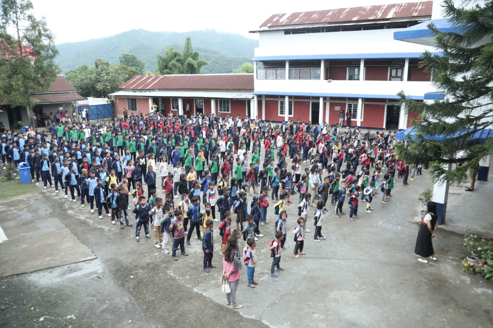 Hundreds of students gathered for morning assembly on the grounds of T.L. Shalom Academy, with the hills of Manipur rising behind the campus.