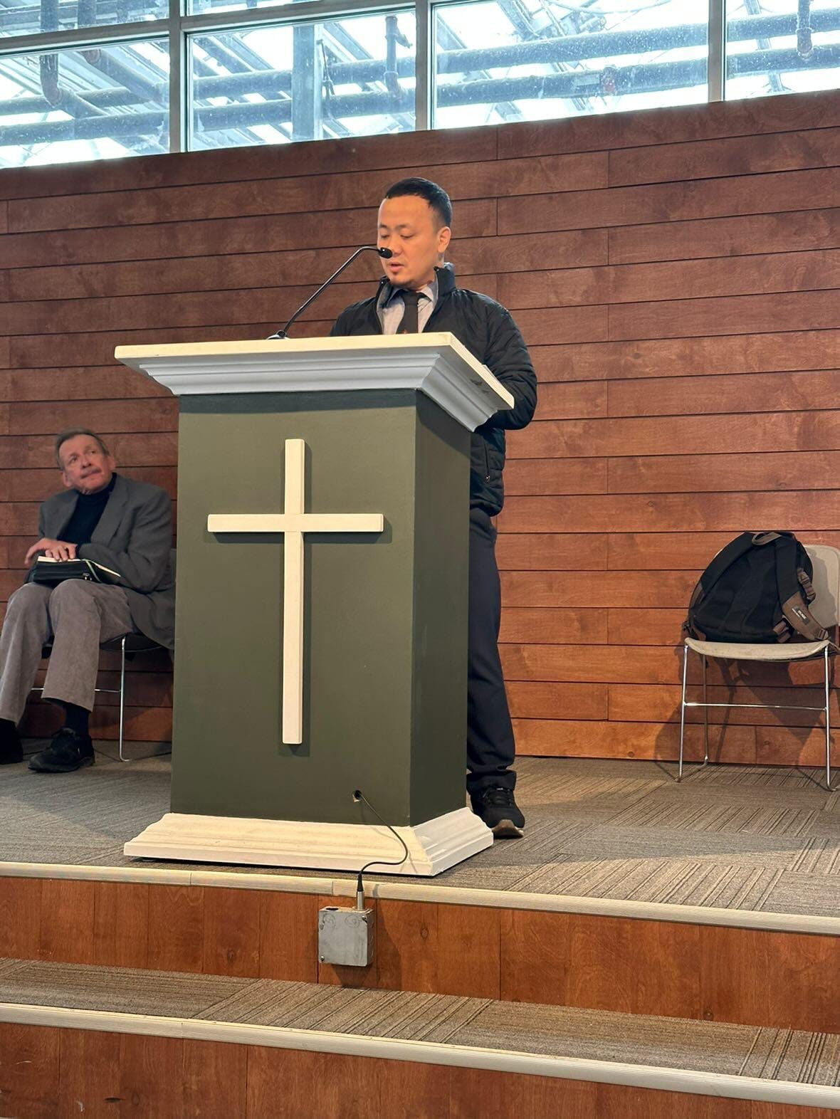 A pastor preaching from a pulpit marked with a cross in Northeast India.