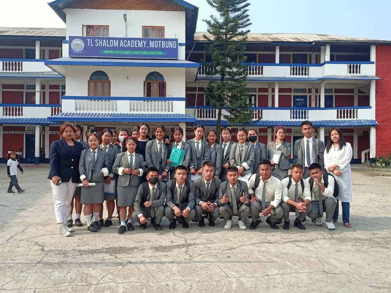 A class of students photographed in front of the T.L. Shalom Academy building.