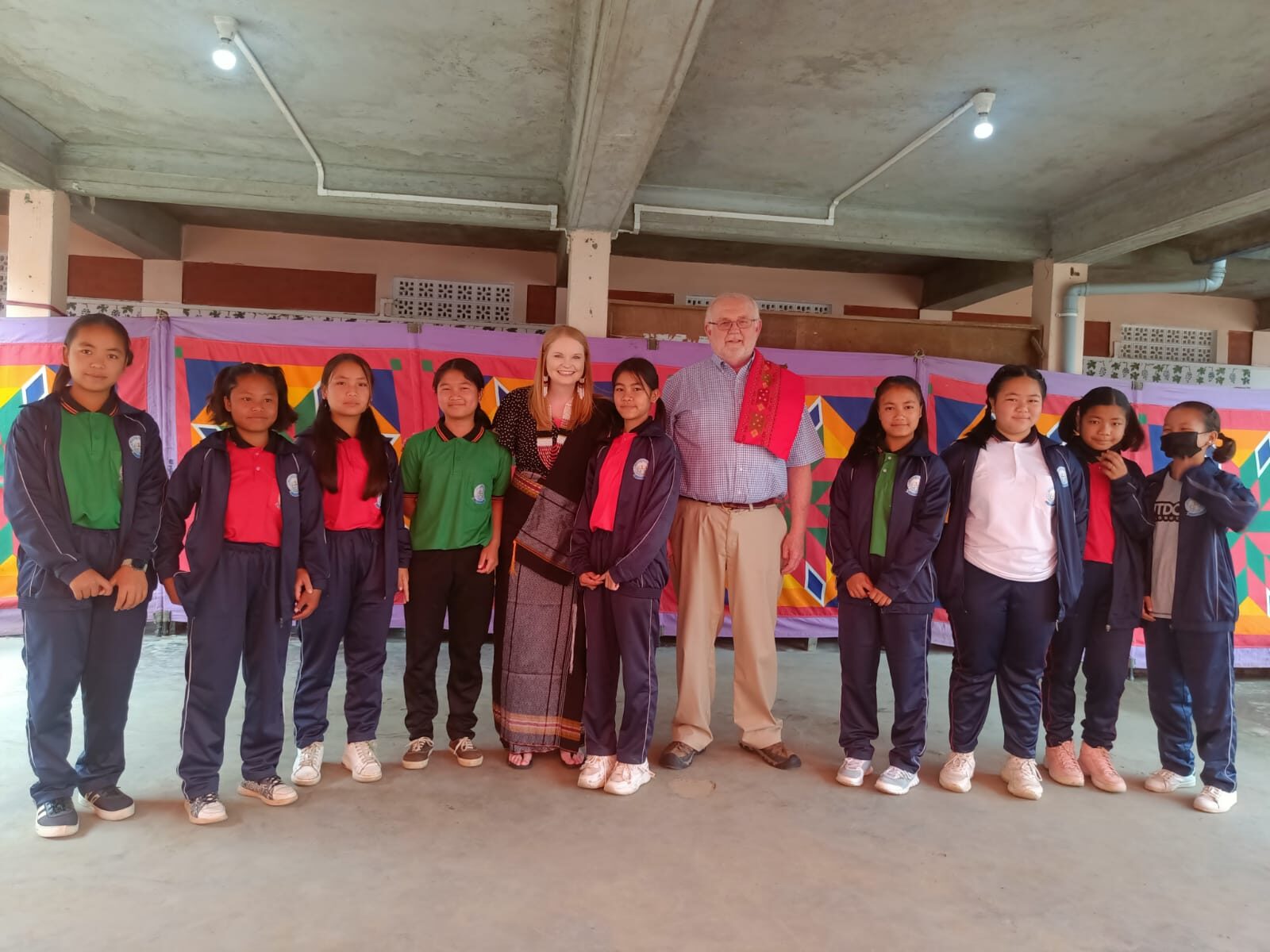 Older students of Shalom Academy standing with a visiting board member under the campus pavilion.